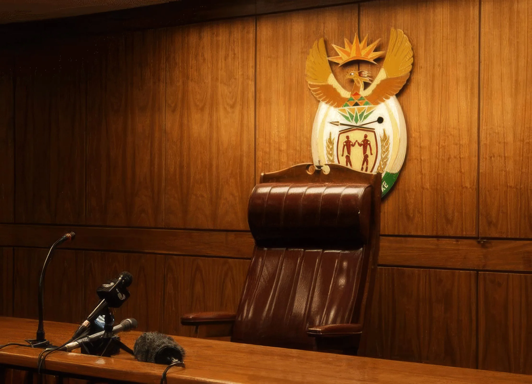 A High Court judge's bench beneath the South African coat of arms, a microphone at the ready.