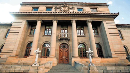 A grand sandstone courthouse facade with columns and arched windows.